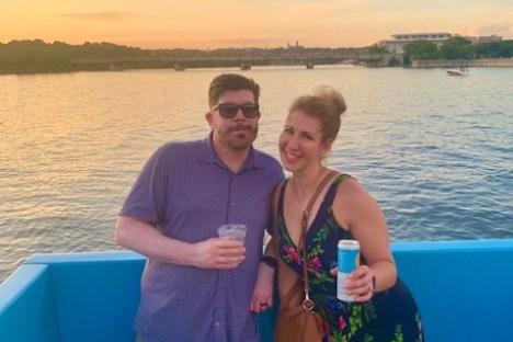 a couple standing next to a body of water posing for the camera