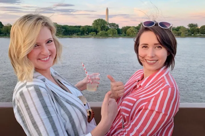 two women smiling next to a body of water