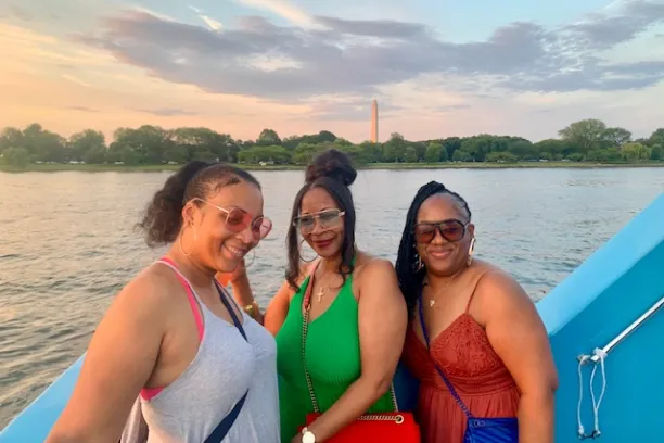 three women standing next to a body of water posing for the camera