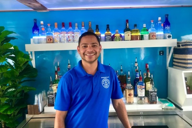 a man in a blue shirt standing in a bar on a boat